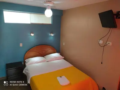a bedroom with a bed with a television on the wall at Hotel Villa Santa Ana in Quillabamba