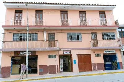 a man standing in front of a pink building at Hospedaje Zaragoza in Ayacucho