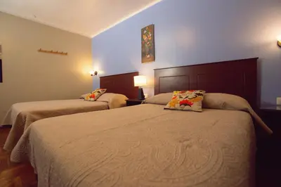 a hotel room with two beds and two lamps at Hospedaje Zaragoza in Ayacucho