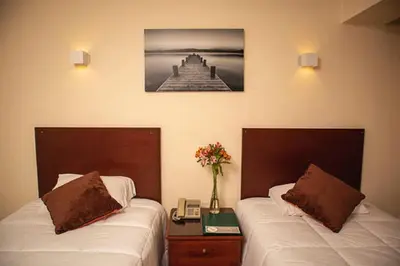 a bedroom with two beds and a table with flowers at Hotel Ferrua in Lima