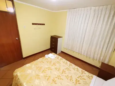 a bedroom with a bed and a dresser and a window at Hospedaje Las Lilas in Huancayo