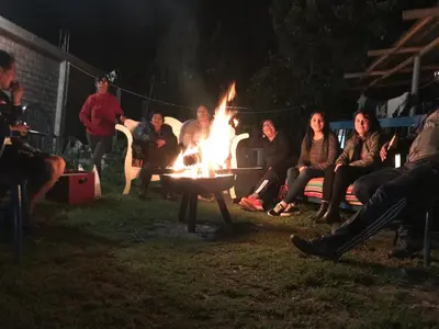 a group of people sitting around a fire at night at Bull House in Urubamba