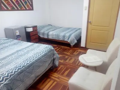 a room with two beds and a chair in it at Peruvian Family Hostal Miraflores in Lima