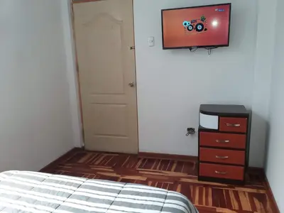 a bedroom with a bed and a tv on the wall at Peruvian Family Hostal Miraflores in Lima