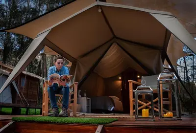 a woman sitting in a tent reading a book at Glamping Chaska Ocupi in Urubamba