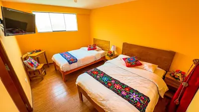 a bedroom with two beds and a tv in it at Andean Atoq Hostel in Cusco