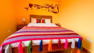 a bedroom with a bed with a colorful bedspread with tassels at Andean Atoq Hostel in Cusco
