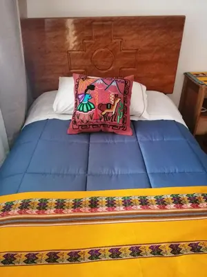 a bed with two pillows on top of it at Kenti's Home Ollantaytambo in Ollantaytambo