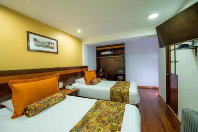 two beds in a room with yellow walls at Posada San Blas in Cusco
