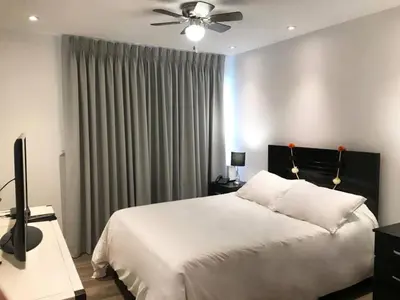 a bedroom with a white bed and a ceiling fan at Céntrico Apartamento Parque Kennedy Miraflores in Lima