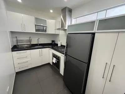 a kitchen with white cabinets and a black refrigerator at Céntrico Apartamento Parque Kennedy Miraflores in Lima