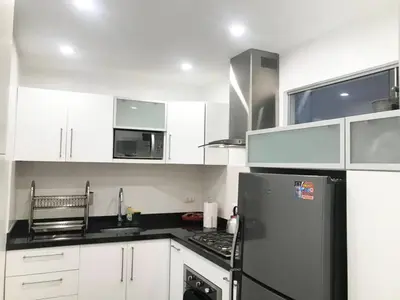 a kitchen with white cabinets and a black refrigerator at Céntrico Apartamento Parque Kennedy Miraflores in Lima