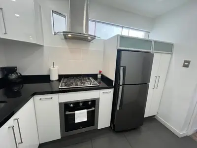 a kitchen with a black refrigerator and white cabinets at Céntrico Apartamento Parque Kennedy Miraflores in Lima