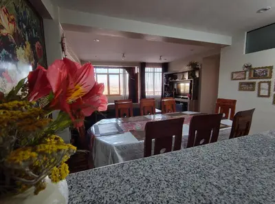 a dining room with a table and chairs and a vase of flowers at El Balcón del Sol in Cusco