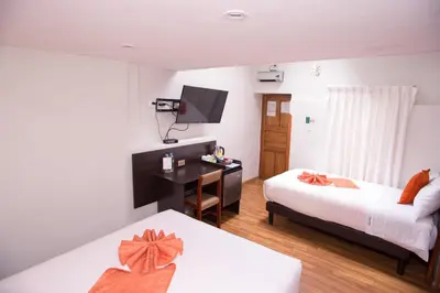 a bedroom with two beds and a desk and a television at Hotel Arcangel in Cusco