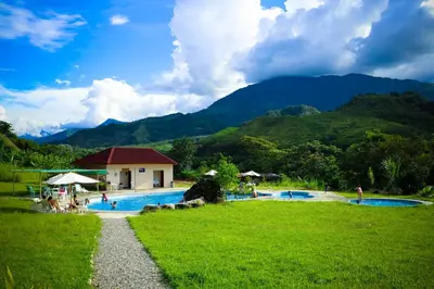 a resort swimming pool with mountains in the background at Mercedes Lodge in San Ramón