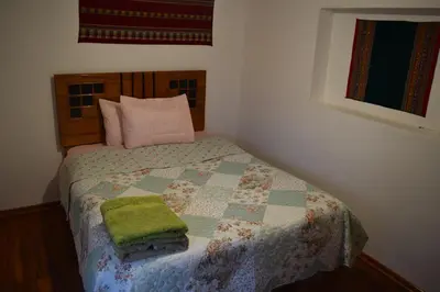a bedroom with a bed with a green blanket and pillows at Carlos Guest House 3 Cusco in Cusco