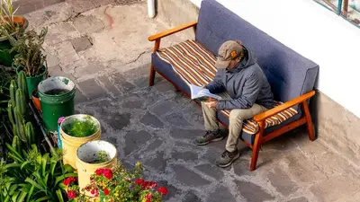 a man sitting on a bench reading a book at La Estación San Pedro in Cusco