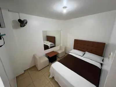 a small bedroom with a bed and a mirror at Hospedaje Senegal cerca al aeropuerto in Lima