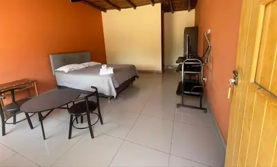 a room with a bed and a table and a television at Hospedaje La Huega in Ica