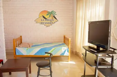 a room with a bed and a desk with a computer at Hospedaje La Huega in Ica