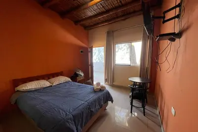 a bedroom with a bed with a blue blanket and a window at Hospedaje La Huega in Ica