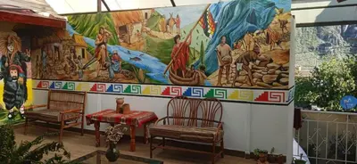 a mural on the side of a building with two chairs at Casa Inka B&B in Ollantaytambo