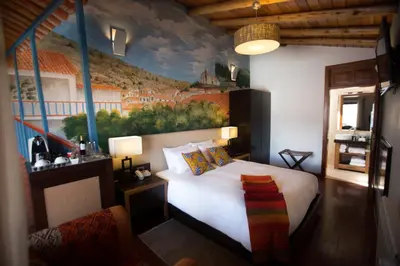 a bedroom with a bed with a painting on the wall at Tocuyeros Boutique Hotel in Cusco