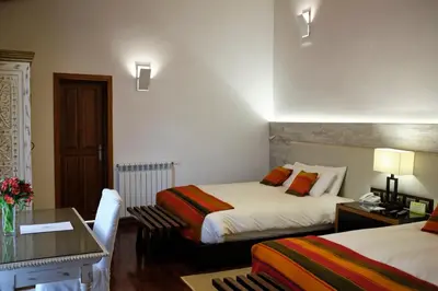 a hotel room with two beds and a table at Tocuyeros Boutique Hotel in Cusco