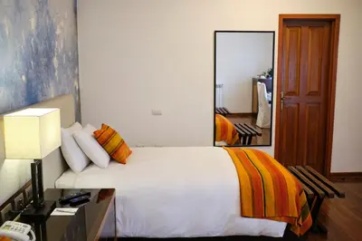 a bedroom with a large white bed with a mirror at Tocuyeros Boutique Hotel in Cusco