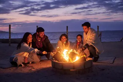 a group of people sitting around a fire on the beach at Casa Andina Select Paracas in Paracas