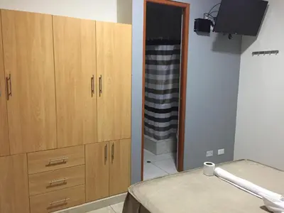 a bedroom with a bed and a dresser and a closet at Hostal Parisuite in Lima