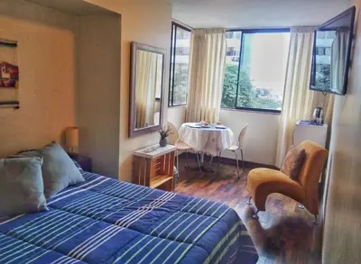 a bedroom with a bed and a table and windows at Amplia habitación con baño in Lima