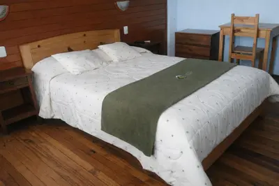 a bedroom with a large white bed with a wooden headboard at Hostal Arias in Oxapampa