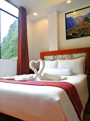 a bedroom with a bed with two swans forming a heart at Hotel Machupicchu Inn in Machu Picchu