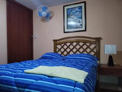 a bed with a blue comforter in a bedroom at Hostal Turístico El Cajamarquez in Lima