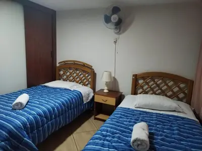 a bedroom with two beds and a fan at Hostal Turístico El Cajamarquez in Lima