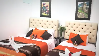 a bedroom with two beds with orange and white sheets at Imperial Golden House Inn in Cusco