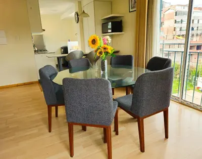 a dining room with a glass table with chairs and a vase of flowers at Fiflos Apartament in Cusco
