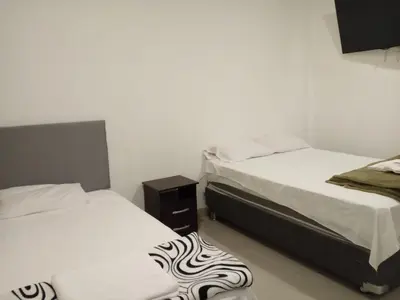 a room with two beds and a nightstand between them at Keylas Hotel in Ica