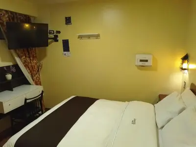 a bedroom with a bed and a desk and a television at CasaHotel Centro - Huancayo in Huancayo