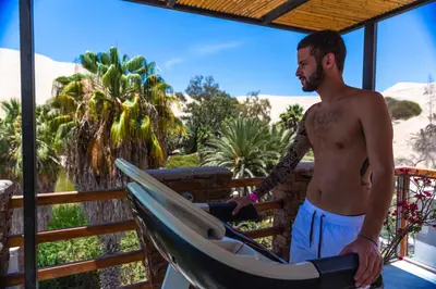 a man is holding a surfboard in a canoe at Banana's Adventure Hostel in Ica