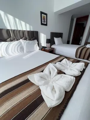 two beds with white towels on them in a room at Hotel Andes Urubamba in Urubamba