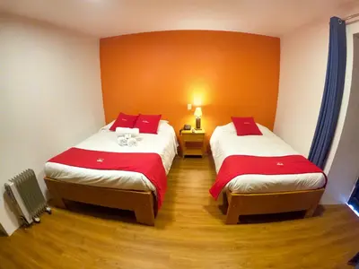 a room with two beds with red and white sheets at Hotel Casa Campesina in Cusco
