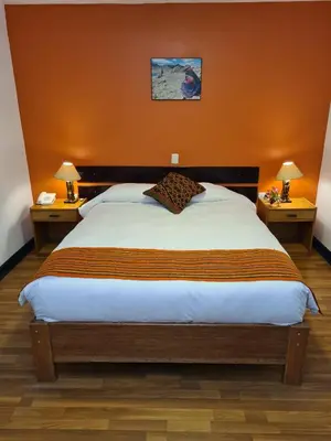 a bedroom with a large bed with orange walls at Hotel Casa Campesina in Cusco