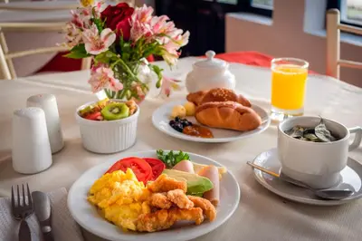 a table with plates of breakfast foods and a cup of orange juice at La Casa de Fray Bartolome in Cusco