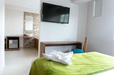 a bedroom with a green bed with a television on the wall at Hotel Monte Cafeto INN in Pichanaki