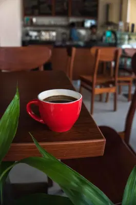 a red cup of coffee sitting on a wooden table at Hotel Monte Cafeto INN in Pichanaki