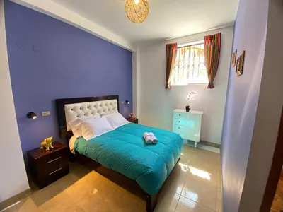 a bedroom with a bed with a blue wall at BROTHERs HOUSE in Cusco