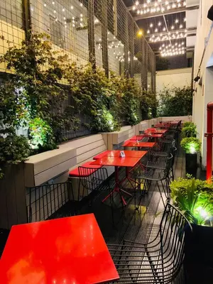 a row of red tables in a restaurant with plants at Radisson RED Miraflores in Lima